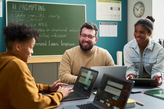 Teacher and two students smiling while exploring an AI tool together in class